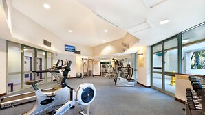 A gym with cardio machines, weight equipment, and a large mirror.