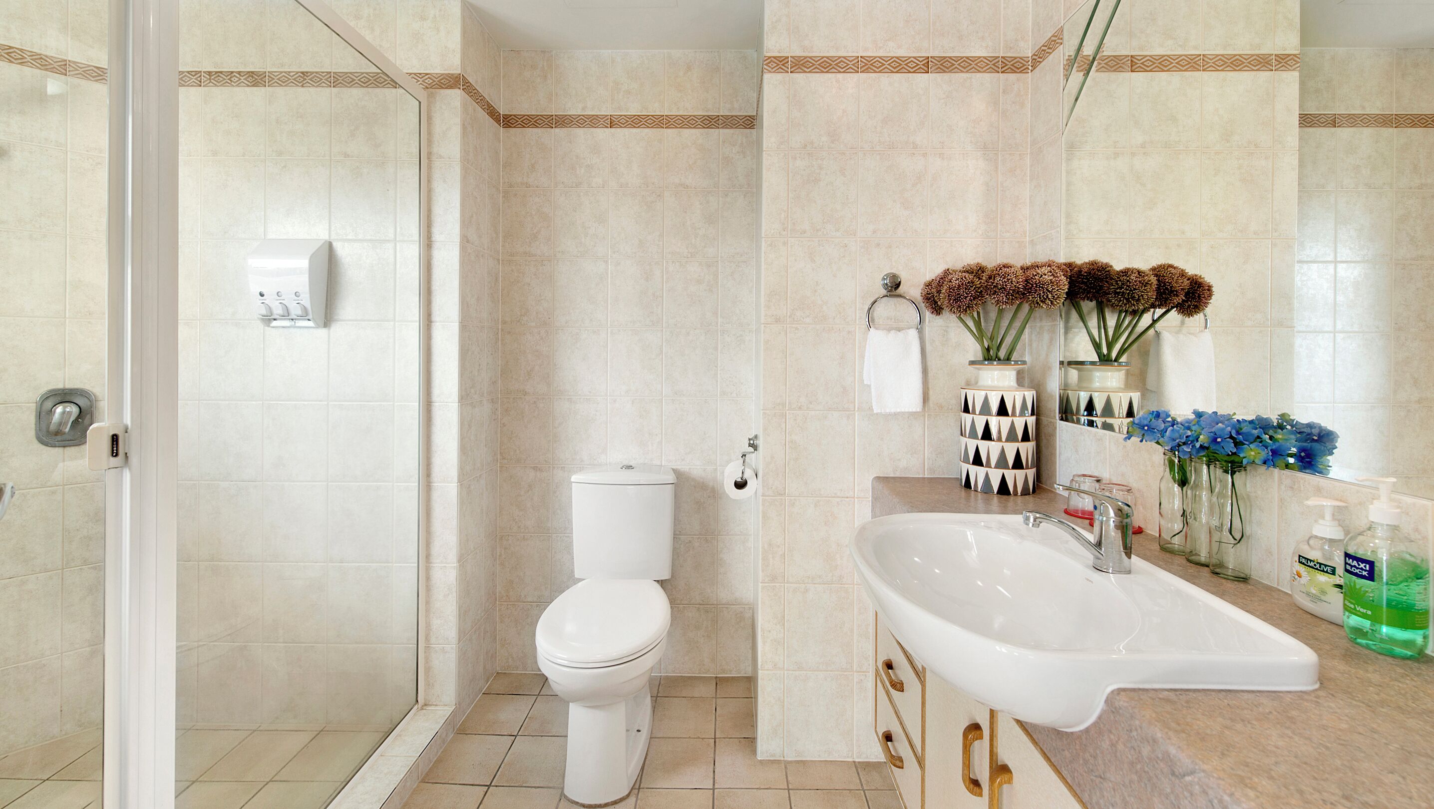 A modern bathroom with a toilet, shower, sink, and decorative items.