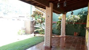 A covered patio area with brick pillars, a tiled floor, and hanging lanterns. - Vacation home with pool, fan, barbecue, Wi-Fi, and air conditioning. (Ubatuba)