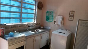 A kitchen with a window, sink, stove, and refrigerator. - Vacation home with pool, fan, barbecue, Wi-Fi, and air conditioning. (Ubatuba)
