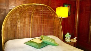 A bed with a woven headboard, a lamp, and a small table with decorative items.