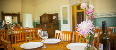 A dining table set with plates, wine glasses, and a vase with flowers.