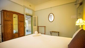 Ein Hotelzimmer mit einem großen Bett, einem Holzschrank und einem kleinen Tisch.