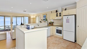 Een moderne keuken met een centraal eiland, witte kasten, een inbouwoven en een koelkast.