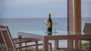Een tafel met een fles wijn en twee glazen, met uitzicht op de zee.
