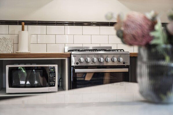 Una cocina equipada con microondas, horno y cocina a gas.