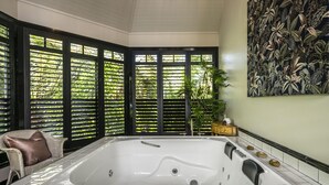 A spacious bathroom with a large bathtub, black-framed windows, and a wall-mounted artwork.
