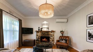 A living room with a stone fireplace, a leather armchair, a television, and a chandelier.