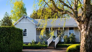Une maison à deux étages avec un porche à l’avant, un escalier et un jardin bien entretenu.