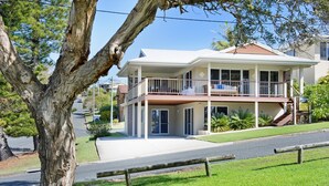 A two-story house with a balcony, a driveway, and a tree in the foreground. - Allure by the Sea - beachfront luxury home (Bonny Hills)