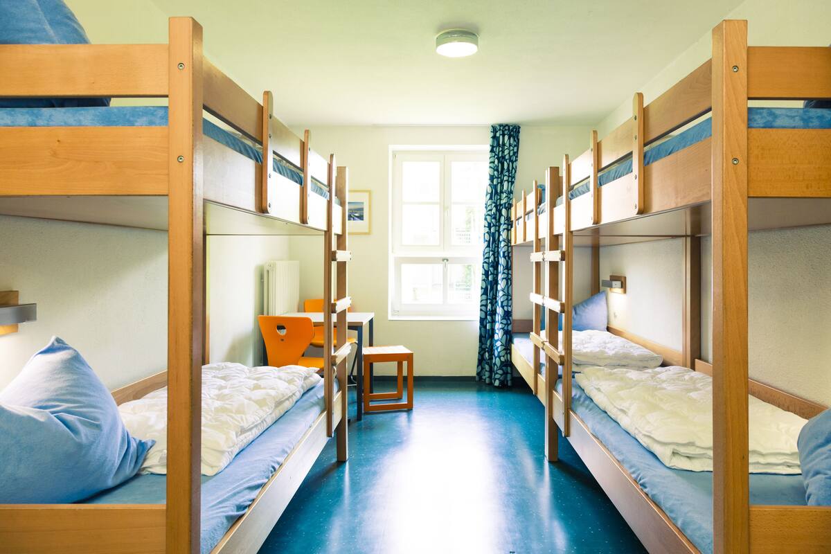 Ein Schlafsaalzimmer mit Etagenbetten, einem Schreibtisch und einem Stuhl.
