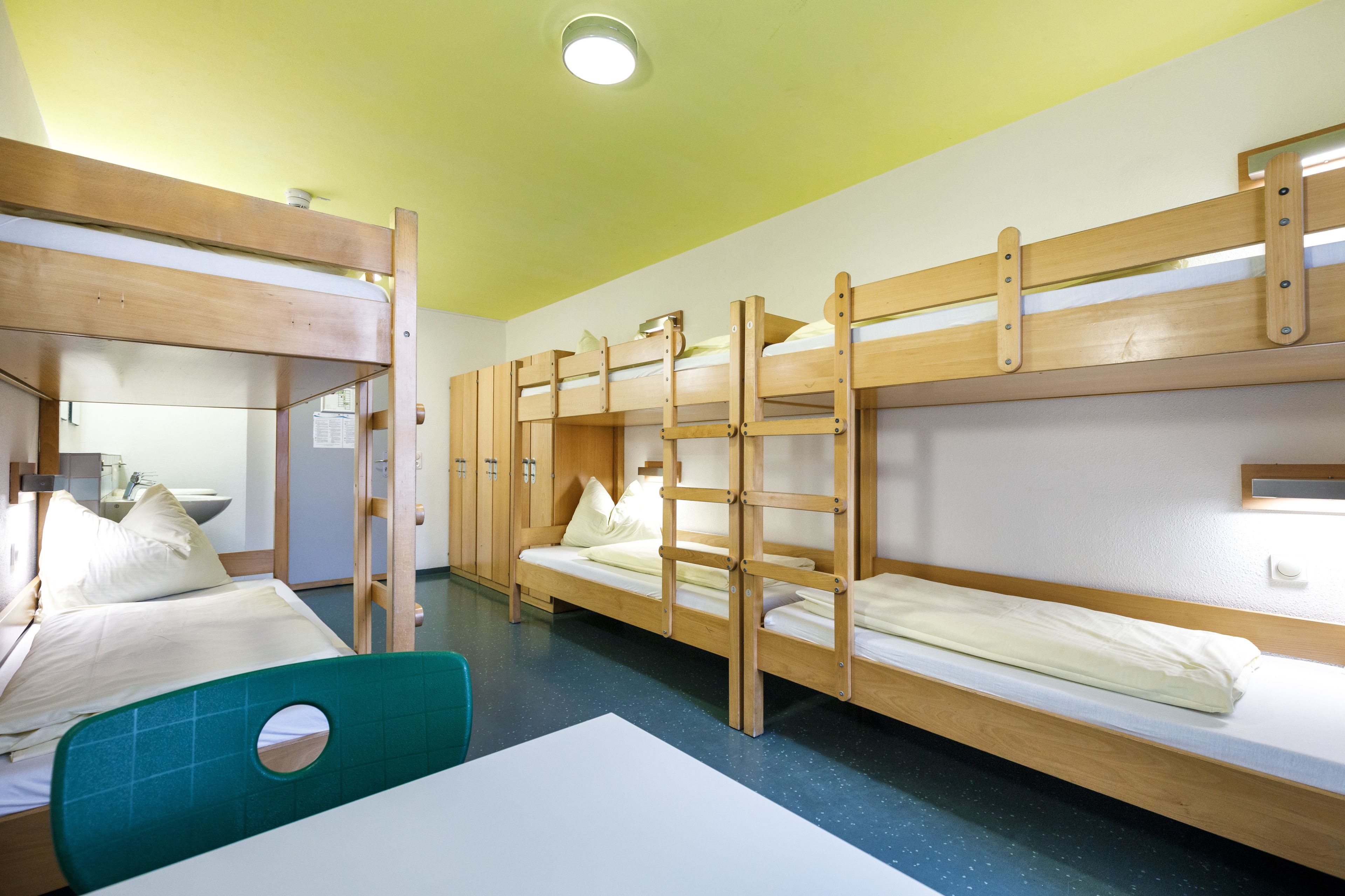 A dormitory room with bunk beds, a desk, and a chair.