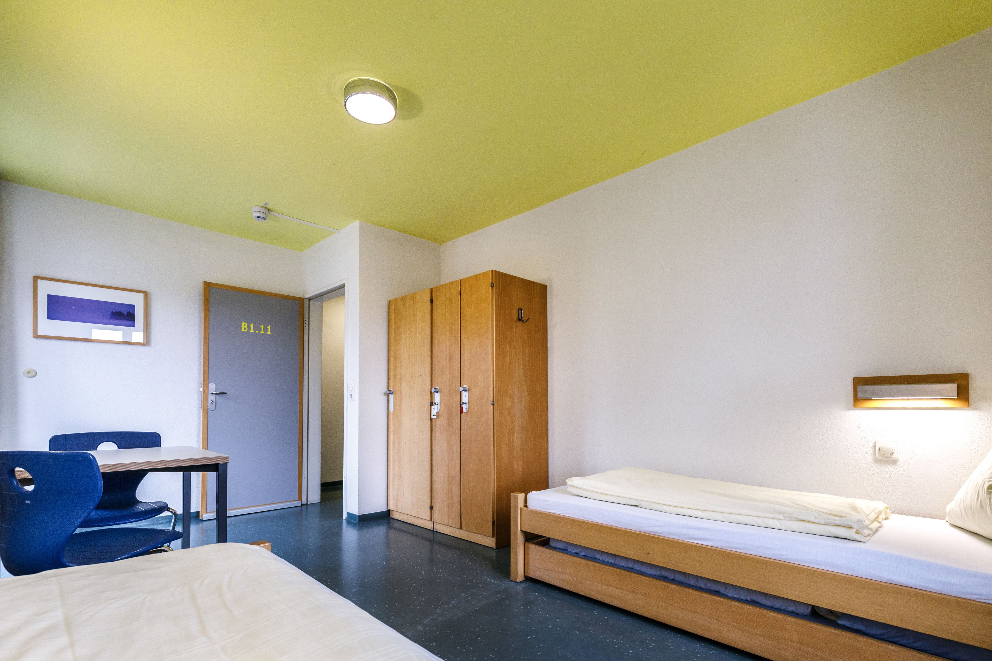 A room with a bed, a desk, a chair, and a wardrobe.
