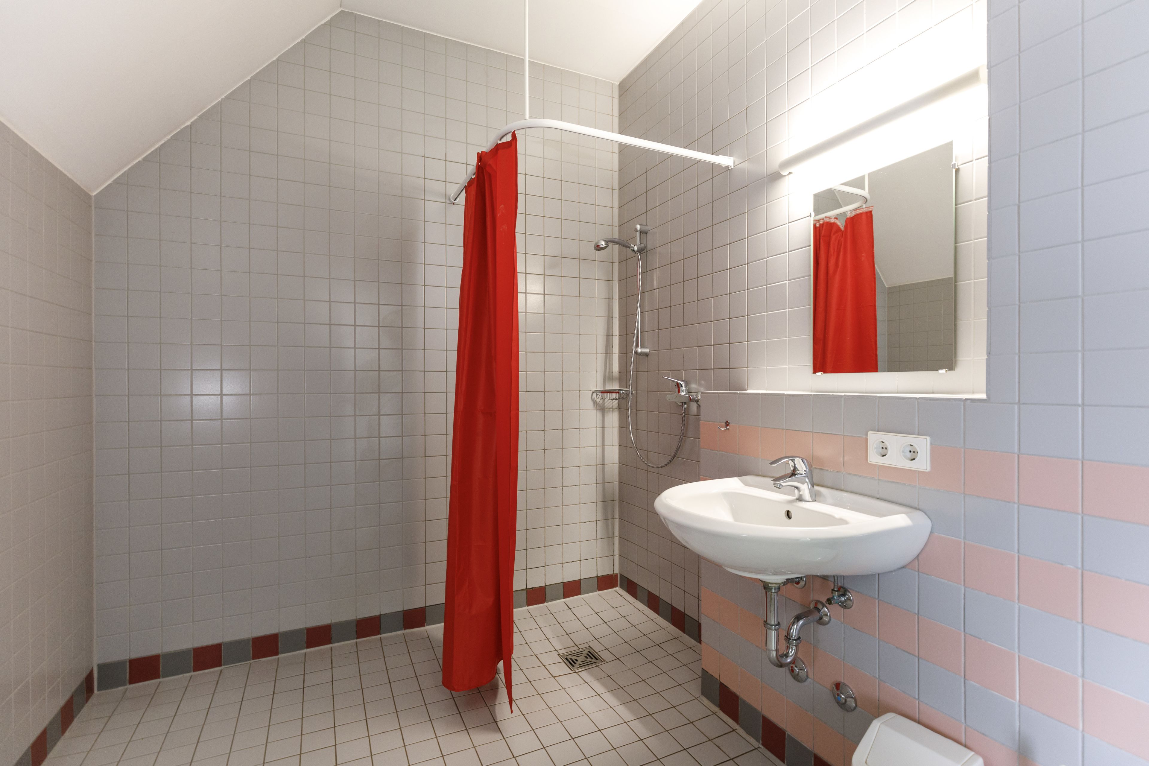 Un bagno con doccia, lavandino e specchio.