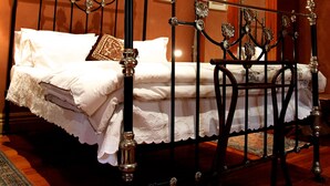 A bedroom with a four-poster bed, a wooden floor, and a patterned rug. - Cafe Spa Suite 1 bedroom (North Adelaide)