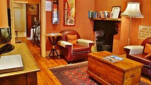 A cozy living room with a fireplace, leather armchairs, a coffee table, and a bookshelf. - Cafe Spa Suite 1 bedroom (North Adelaide)