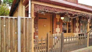 A brick building with a wooden door and a picket fence. - Cafe Spa Suite 1 bedroom (North Adelaide)