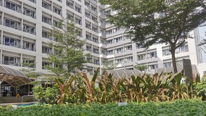 A multi-story building with balconies and a landscaped area with various plants.