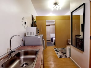 Cozy retreat with a kitchenette, featuring a bed, stainless steel sink, microwave, and refrigerator.