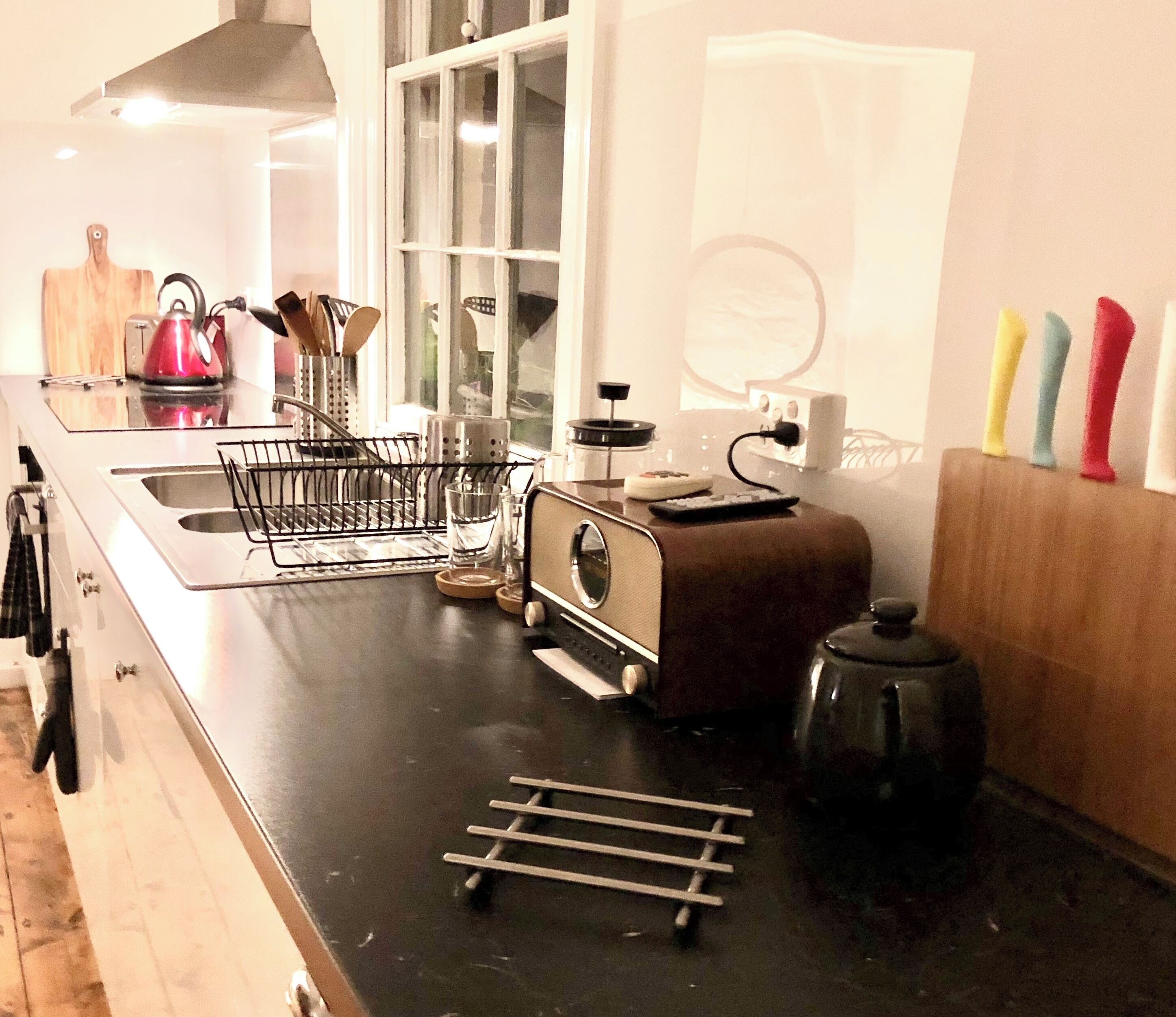 Een keuken met een broodrooster, waterkoker en een afdruiprek.