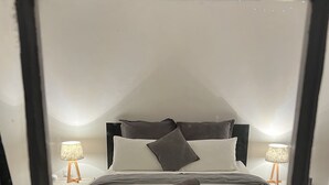 A bedroom with a bed, pillows, a rolled towel, bedside lamps, and a plant. - Cosy Heritage Cottage in Newstead, Central to Daylesford, Maldon & Castlemaine (Newstead)
