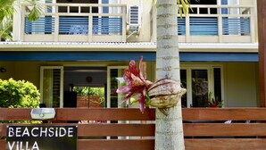 Letrero de Beachside Villa con una valla de madera y una palmera al frente.