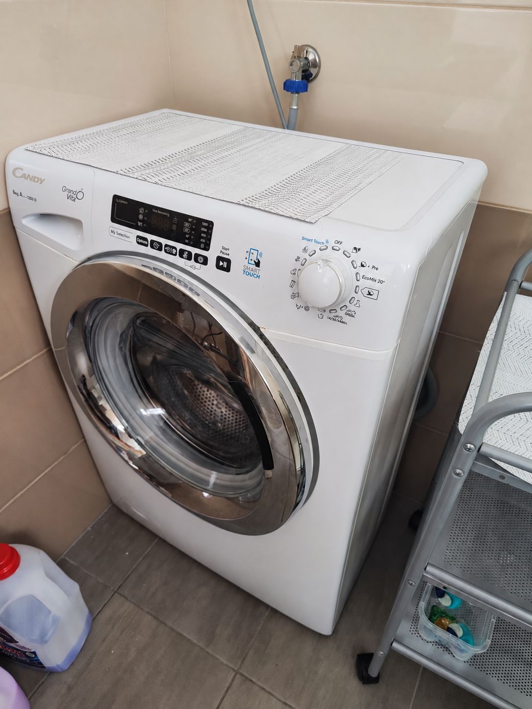Eine Waschmaschine mit Frontlader, einem digitalen Display, Bedienfeld und einem Wasserzulaufschlauch.