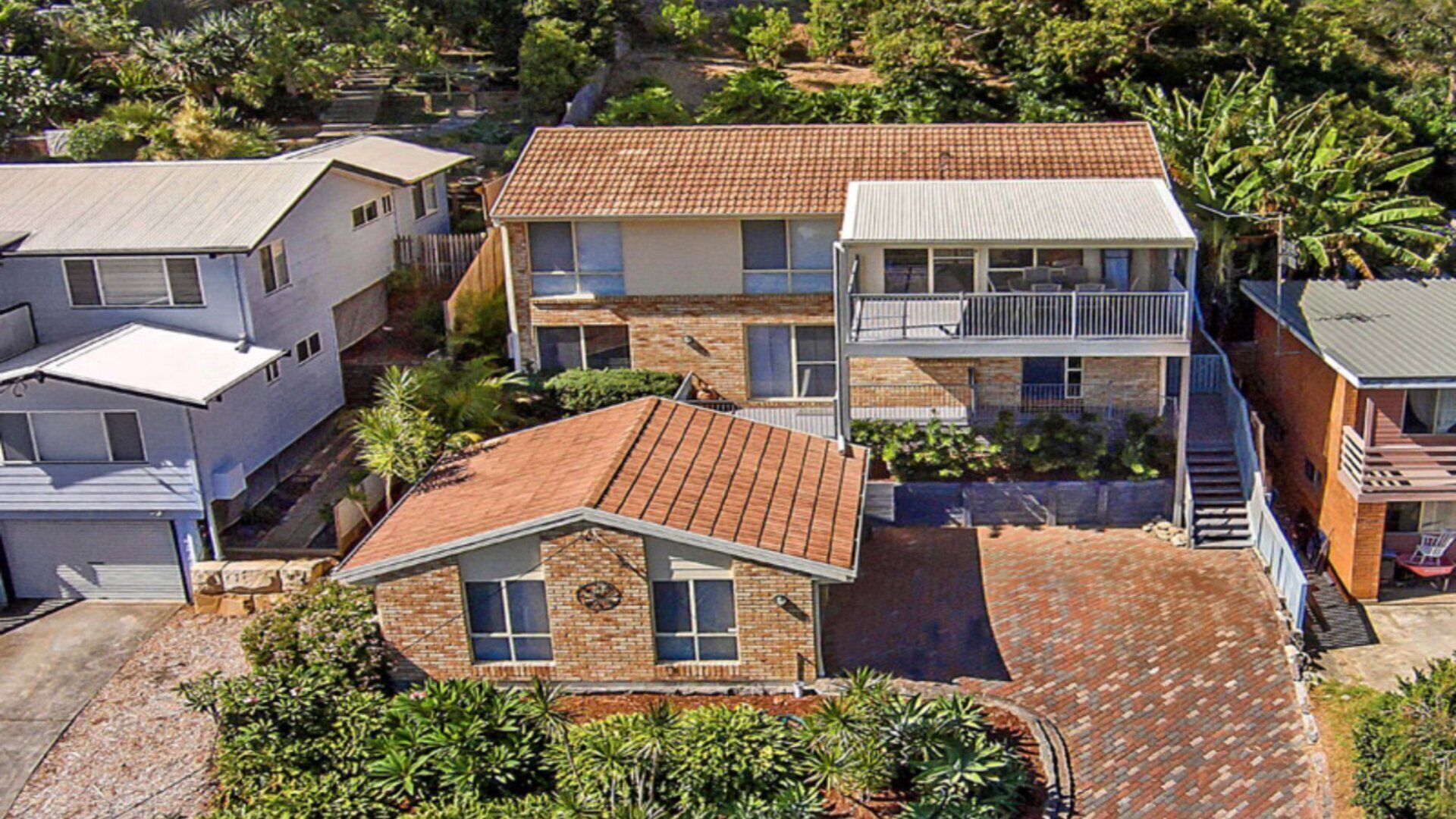 A residential area with multiple houses, including a two-story building with a balcony and a detached house with a garage.