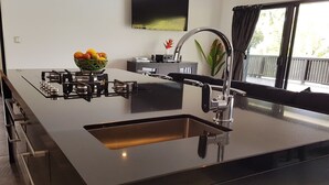 A modern kitchen with a central island, a built-in sink, and a stainless steel faucet. - Boaza Place is situated in Nikao and offers an outdoor swimming pool.  (Puapuautu Tapere)