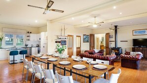 A spacious living area with a dining table set for six, a fireplace, and a television. - Woolamai Park Suits 2-3 Families LARGE 7 Bedrooms (Woolamai)