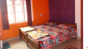 A bedroom with a wooden bed, a window with curtains, and an orange wall. - For delightful stay, visit us (Madikeri)