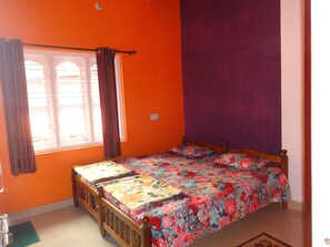 Cozy bedroom with a vibrant wall, a wooden bed, and a floral bedspread.