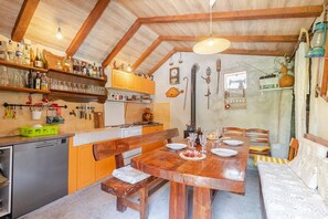 Une cuisine rustique avec des poutres en bois, une table à manger dressée pour quatre personnes et divers appareils de cuisine.