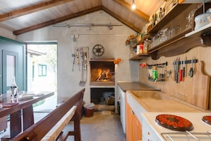 Une cuisine rustique avec un poêle à bois, des poutres apparentes et un coin repas équipé de bancs.