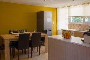 A compact kitchen with a refrigerator, a dining area with chairs and a table, and a fruit basket on the counter. - Nafplio Veranda apartment (Nafplio)
