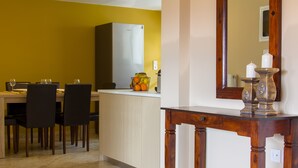 Uma área de refeições com cozinha ao fundo, uma mesa de madeira e cadeiras.