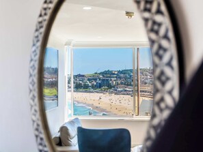 A room with a large window overlooking a beach and cityscape. - Sound of Waves on Bondi (Bondi Beach)