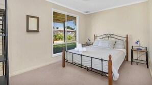 Une chambre à coucher avec un lit, une table de chevet, une lampe, une fenêtre et un miroir.