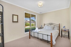 Une chambre à coucher avec un lit, une table de chevet, une lampe, une fenêtre et un miroir.