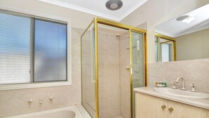 Une salle de bain moderne dotée d’une douche à parois de verre, d’une baignoire et d’un meuble-lavabo avec un évier.