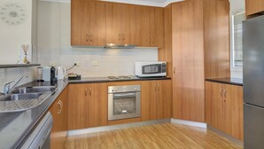 Une cuisine moderne avec des meubles en bois, des appareils électroménagers en acier inoxydable et un four à micro-ondes posé sur le plan de travail.