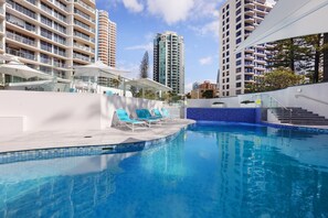 Relax by the pool surrounded by a blue mosaic tile design and lounge chairs.