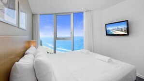 A hotel room with a large bed, a TV on the wall, and a view of the ocean. - Apartment 22502. Located high on the 25th floor of this famous resort hotel (Surfers Paradise)