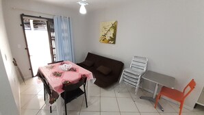 Ein Wohnzimmer mit Esstisch, Sofa, Sessel und Deckenventilator.