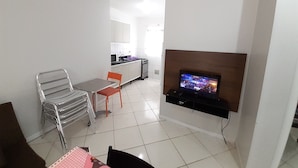 Ein kompakter Wohnbereich mit Küchenzeile, einem Essbereich mit Stühlen, einem an der Wand befestigten Fernseher und einem Kamin.