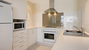 Efficient kitchen with microwave, double oven, and stainless steel sink.