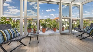 A conservatory with a glass ceiling, potted plants, and seating areas. - Enjoy your private terrace near City Park! (Budapest)