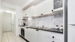 Eine moderne Küche mit weißen Schränken, einer Marmor-Spritzschutzleiste und einem Edelstahl-Spülbecken.