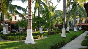 Un complexe hôtelier doté de palmiers, d’une pelouse bien entretenue et d’un sentier.
