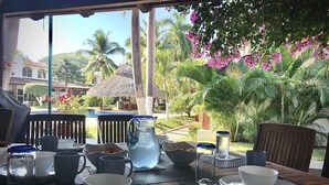 Une table dressée pour le petit-déjeuner, avec vue sur un jardin tropical et une piscine.